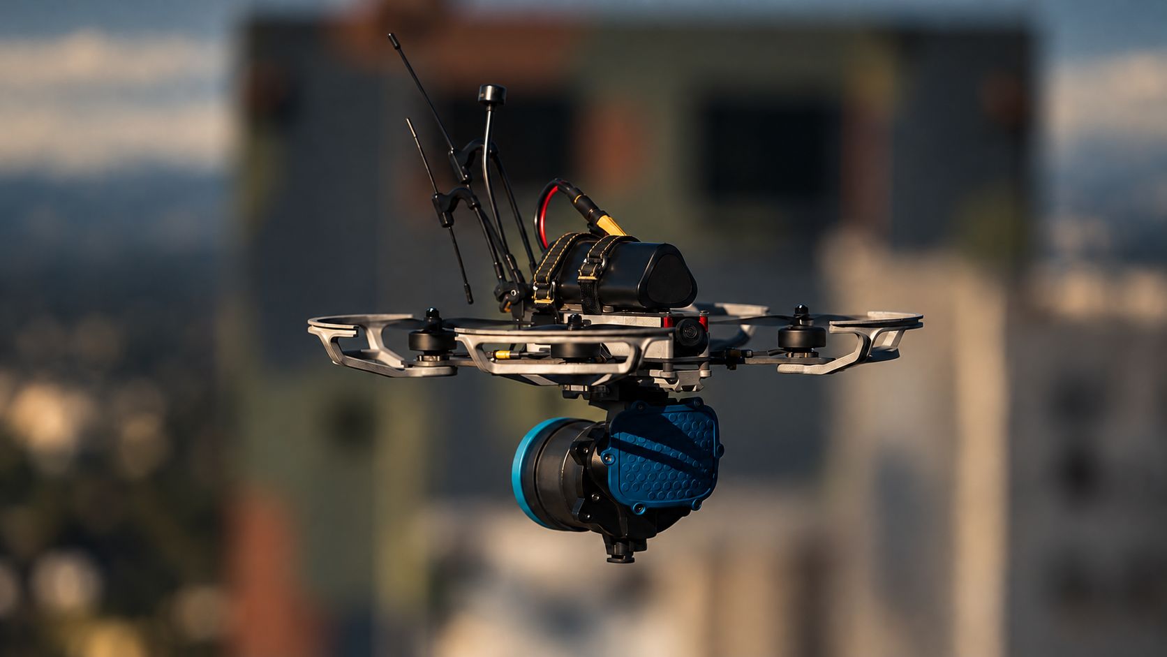 FPV drone with gimbal payload in flight against a city backdrop
