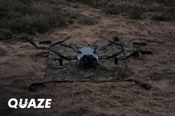 Quaze logo over a drone on a wireless charging pad in the field